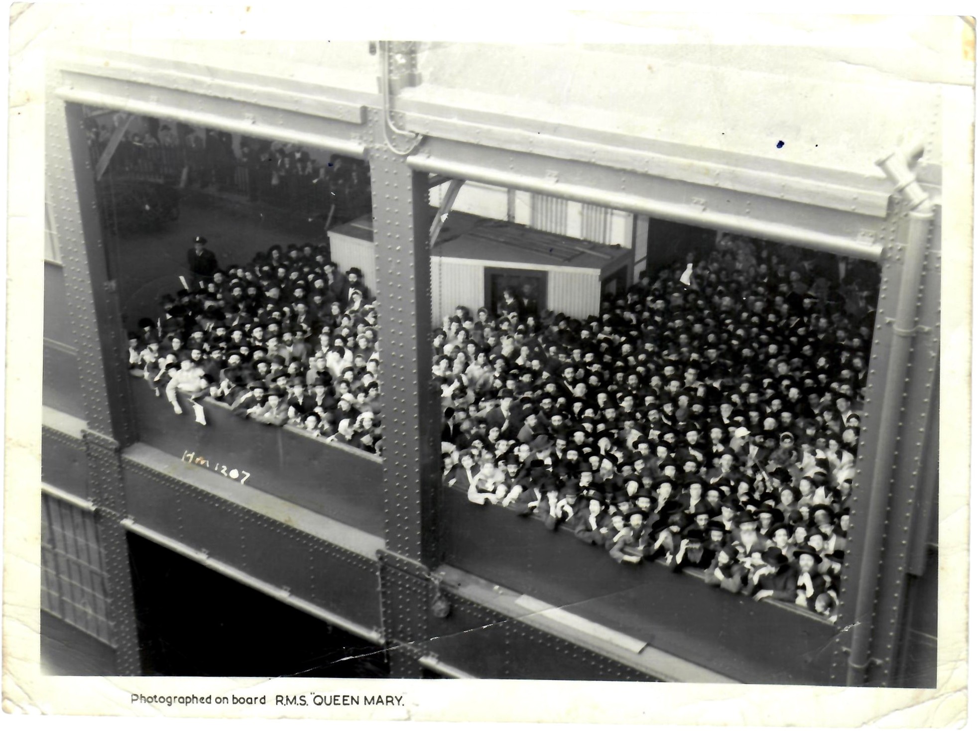 Photograph from the deck of the Queen Mary looking down on a crowd on an upper pier gallery